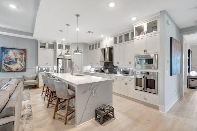 kitchen with wall chimney range hood, stainless steel appliances, open floor plan, a kitchen breakfast bar, and tasteful backsplash