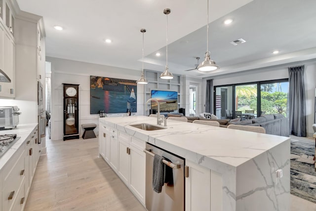 kitchen featuring visible vents, a kitchen island with sink, a sink, stainless steel appliances, and open floor plan