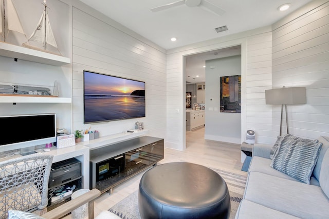 living area featuring visible vents, a ceiling fan, recessed lighting, wooden walls, and light wood-style floors