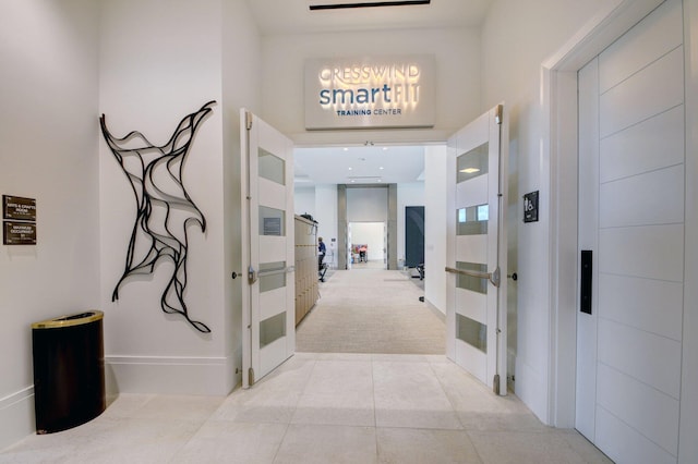 hall featuring light tile patterned flooring and light colored carpet