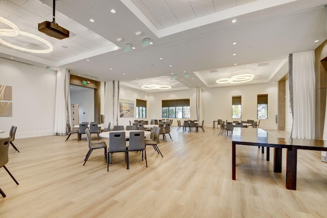 dining room with baseboards, a raised ceiling, and light wood-style flooring