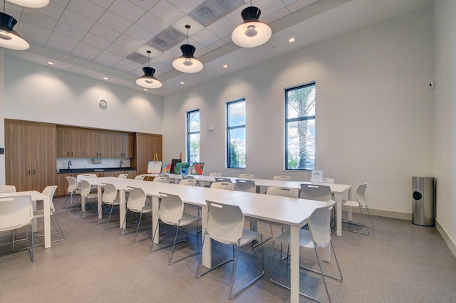 dining room with a raised ceiling, recessed lighting, a paneled ceiling, baseboards, and a towering ceiling