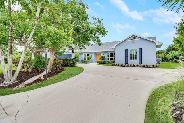 ranch-style house featuring stucco siding, central air condition unit, concrete driveway, and a front yard