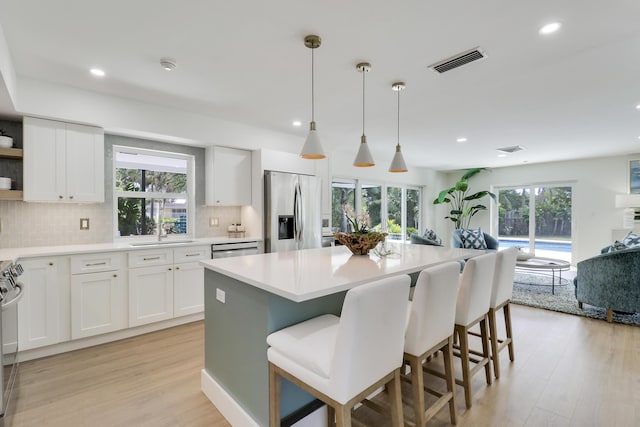 kitchen featuring tasteful backsplash, visible vents, light wood-style floors, stainless steel appliances, and a sink