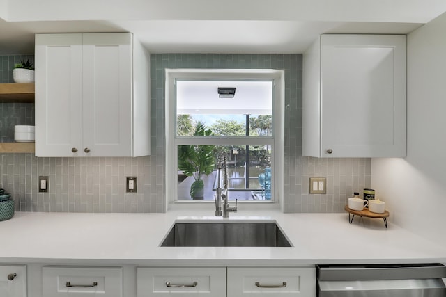 kitchen with a sink, light countertops, stainless steel dishwasher, white cabinets, and open shelves