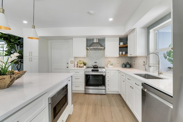 kitchen featuring a sink, stainless steel appliances, backsplash, and wall chimney exhaust hood