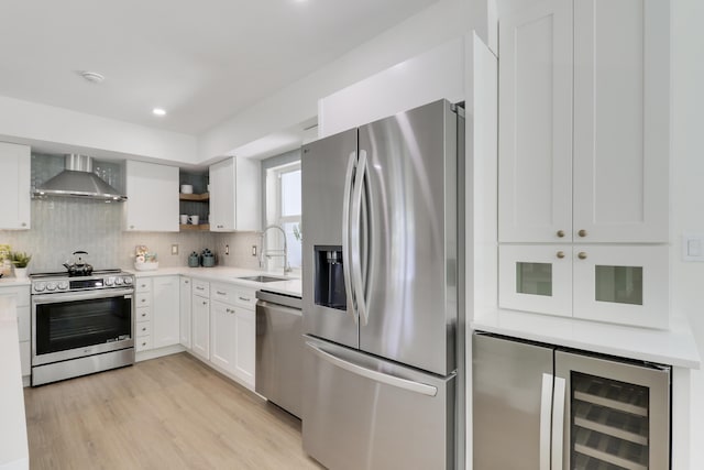 kitchen with beverage cooler, a sink, stainless steel appliances, wall chimney exhaust hood, and decorative backsplash