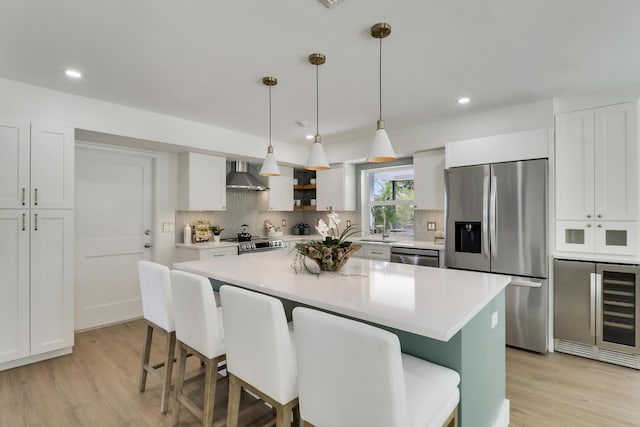 kitchen with stainless steel appliances, wine cooler, wall chimney exhaust hood, and a kitchen breakfast bar