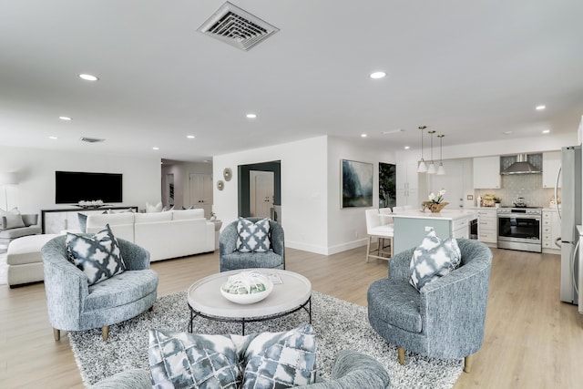 living area with light wood finished floors, visible vents, recessed lighting, and baseboards