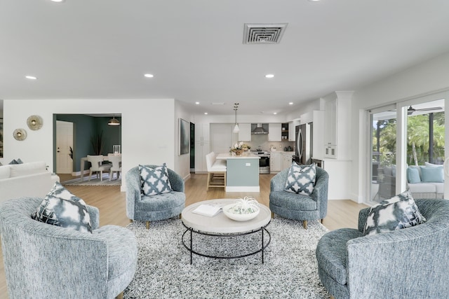 living room with recessed lighting, light wood-style floors, visible vents, and baseboards