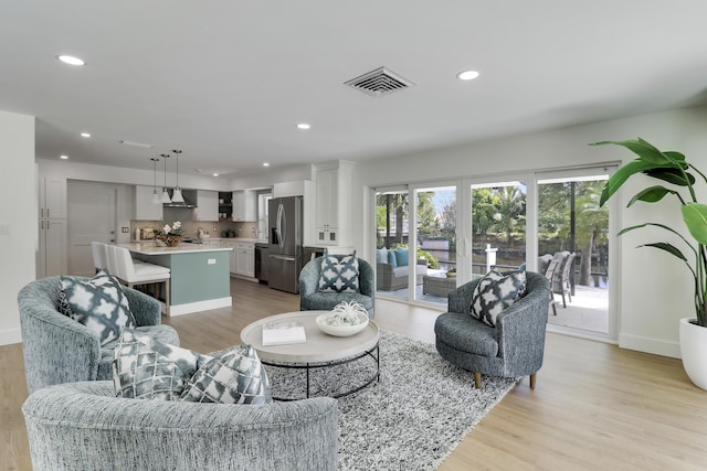 living area with recessed lighting, visible vents, and light wood finished floors