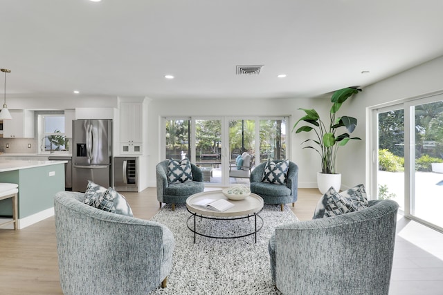 living room featuring wine cooler, visible vents, recessed lighting, and light wood finished floors