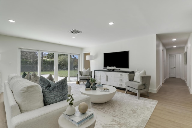 living room with recessed lighting, visible vents, light wood finished floors, and baseboards