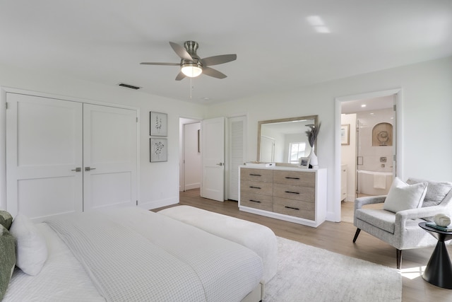 bedroom featuring visible vents, ensuite bathroom, wood finished floors, a closet, and baseboards