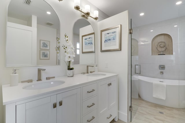 bathroom with a soaking tub, double vanity, visible vents, and a sink