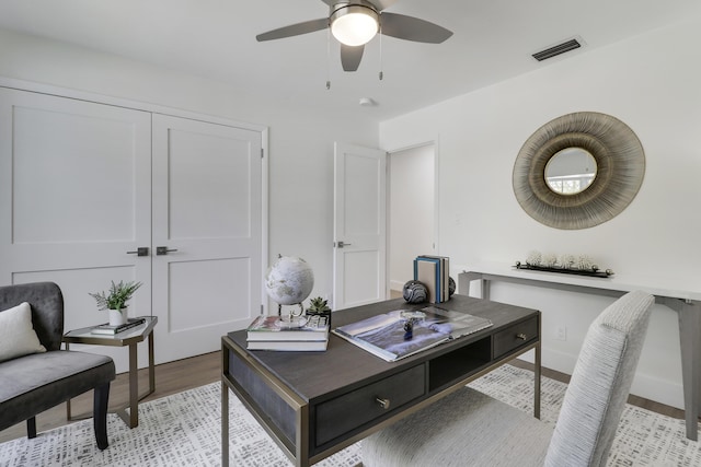 office space with visible vents, baseboards, light wood-style floors, and ceiling fan