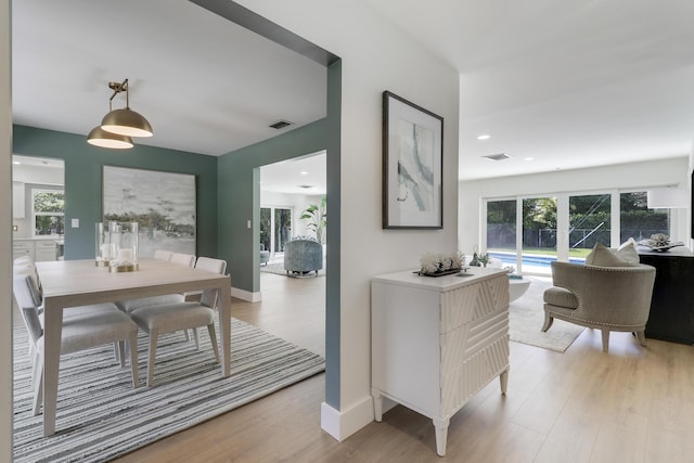 dining space featuring light wood finished floors, visible vents, and baseboards