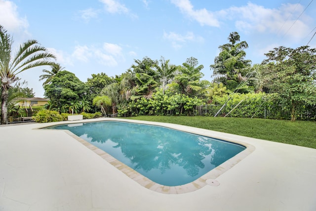 pool with a patio area, a lawn, and fence