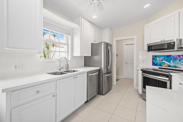 kitchen featuring a sink, stainless steel appliances, white cabinets, light tile patterned flooring, and decorative backsplash