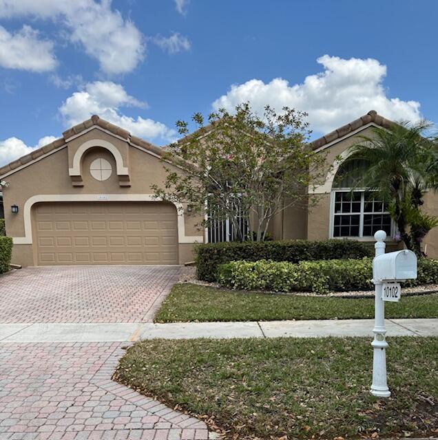 10102 Diamond Lake Rd, Boynton Beach, FL 33437 - mediterranean / spanish-style home with stucco siding, a tiled roof, decorative driveway, and a garage