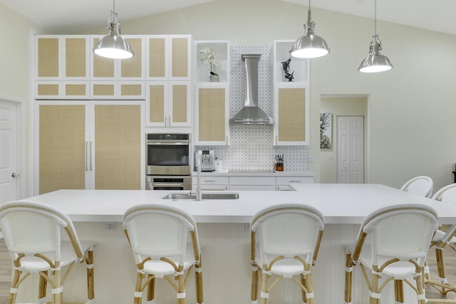 kitchen with lofted ceiling, wall chimney range hood, light countertops, and backsplash