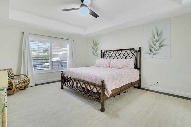 bedroom with a tray ceiling, a ceiling fan, and baseboards