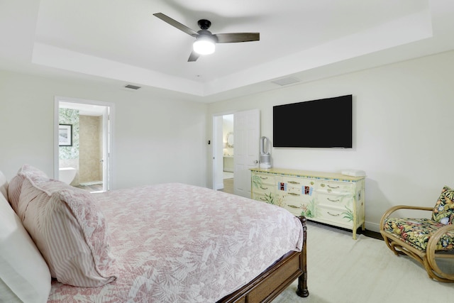 bedroom with ensuite bath, visible vents, a raised ceiling, and a ceiling fan