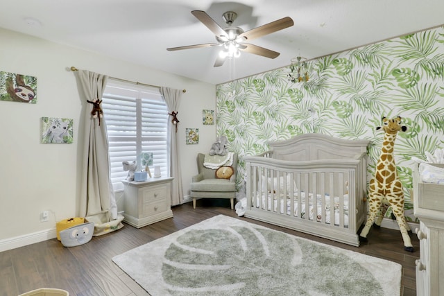 bedroom with a nursery area, wallpapered walls, baseboards, and wood finished floors