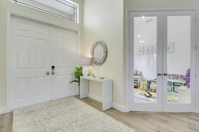 entrance foyer with baseboards, wood finished floors, and french doors