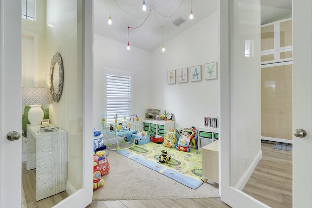 rec room with lofted ceiling, visible vents, and wood finished floors