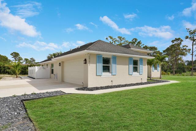 view of side of home with a garage, concrete driveway, a yard, and stucco siding