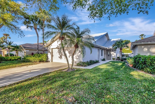 view of front of home featuring stucco siding, an attached garage, a front yard, metal roof, and driveway