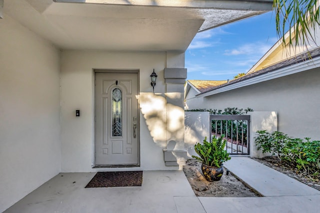 view of exterior entry featuring a gate and stucco siding