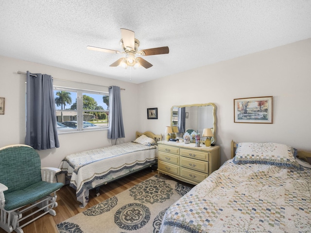 bedroom featuring a textured ceiling, ceiling fan, and wood finished floors