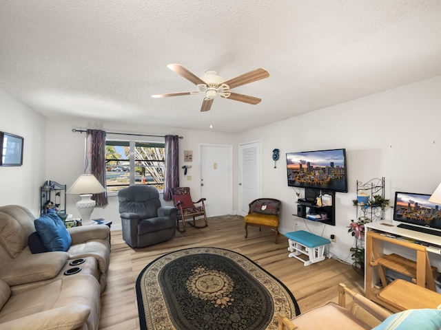 living room with a textured ceiling, light wood-style flooring, and a ceiling fan