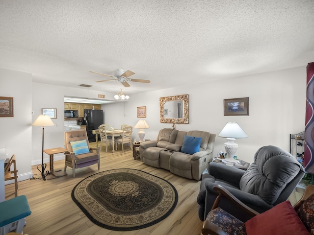 living area featuring visible vents, ceiling fan, a textured ceiling, and light wood finished floors