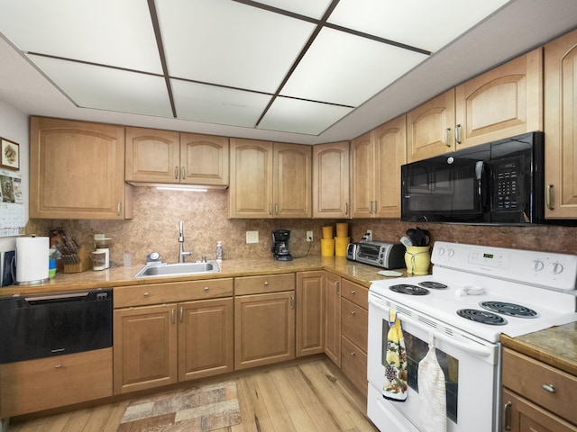 kitchen with black microwave, a sink, light wood-style floors, light countertops, and white range with electric stovetop