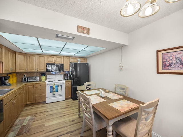 kitchen with visible vents, a sink, a textured ceiling, light wood-type flooring, and black appliances