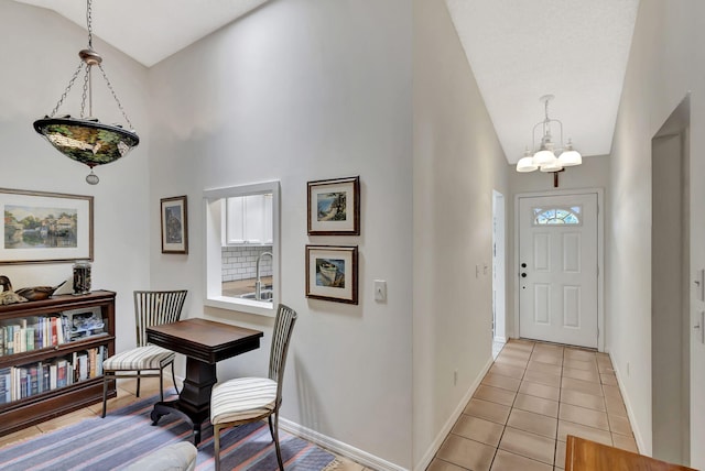 entryway with light tile patterned floors, baseboards, a notable chandelier, and lofted ceiling