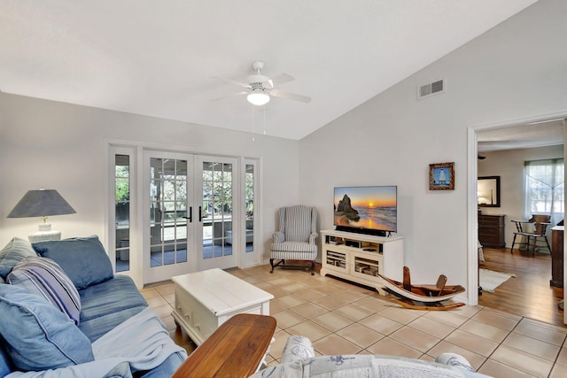 living room with french doors, visible vents, light tile patterned flooring, and vaulted ceiling