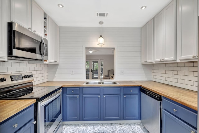 kitchen with visible vents, blue cabinetry, a sink, appliances with stainless steel finishes, and butcher block counters