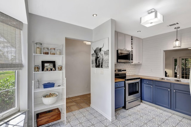 kitchen featuring visible vents, blue cabinetry, light tile patterned floors, appliances with stainless steel finishes, and a sink