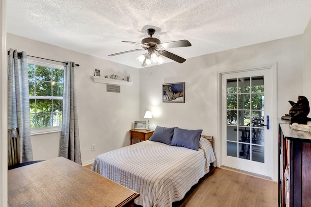 bedroom with access to exterior, baseboards, ceiling fan, wood finished floors, and a textured ceiling