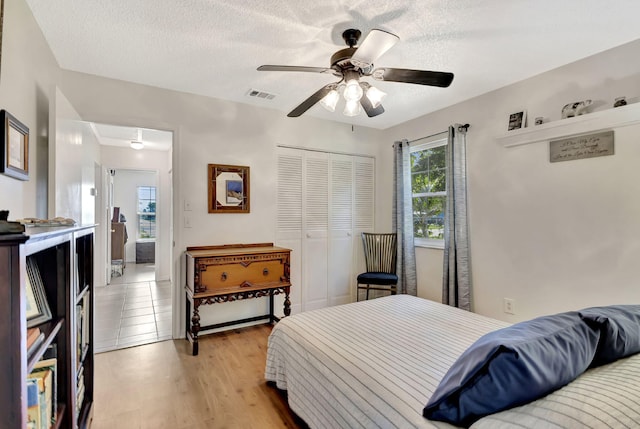 bedroom featuring visible vents, light wood-style floors, a closet, and a textured ceiling