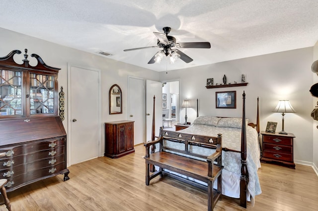 bedroom featuring a textured ceiling, a ceiling fan, visible vents, and light wood-type flooring