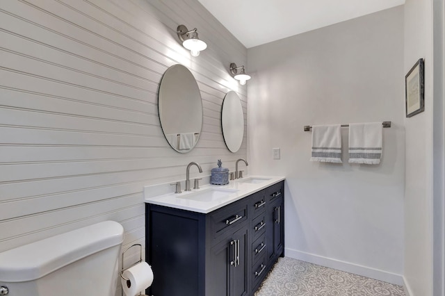 bathroom featuring double vanity, toilet, baseboards, and a sink