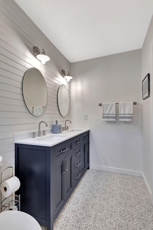 bathroom featuring a sink, baseboards, toilet, and double vanity