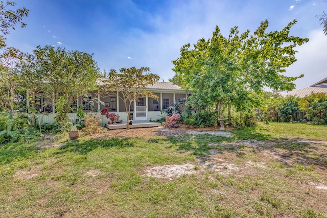 back of property featuring a lawn, a standing seam roof, fence, a sunroom, and metal roof