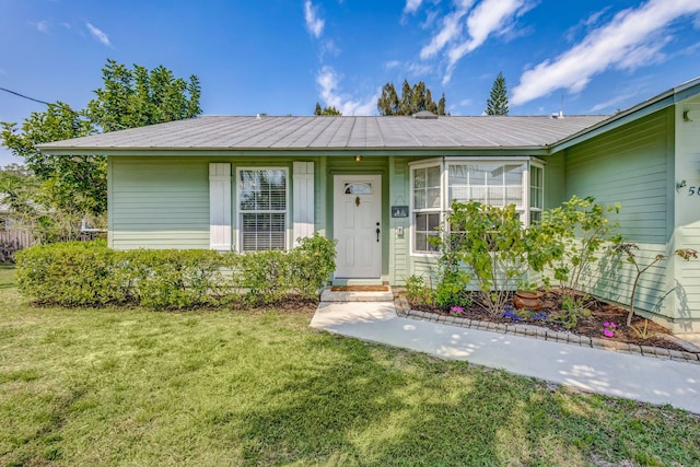 ranch-style home featuring metal roof and a front lawn