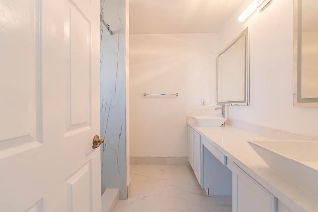 full bath with double vanity, marble finish floor, and a sink